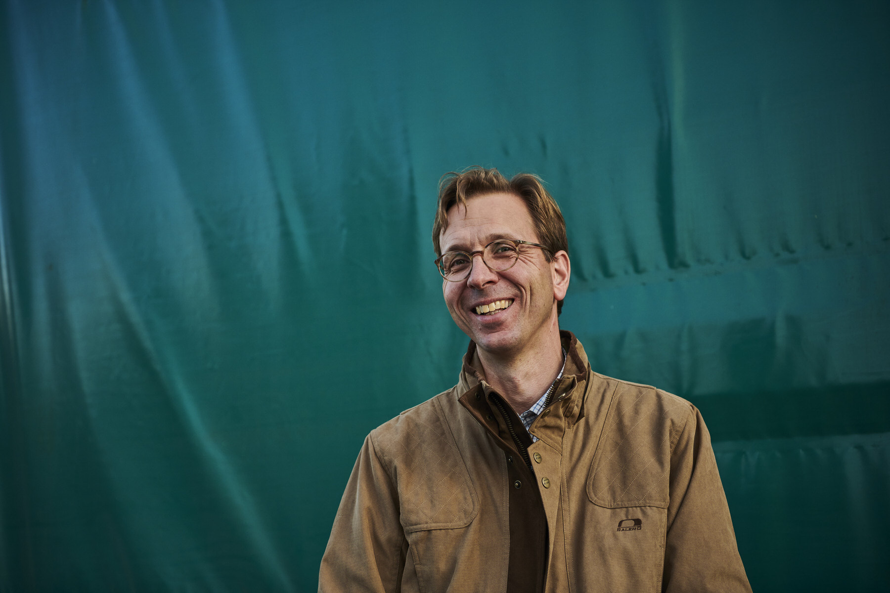 Damien Devos tussen de bomen van zijn boomkwekerij, gekleed in Baleno